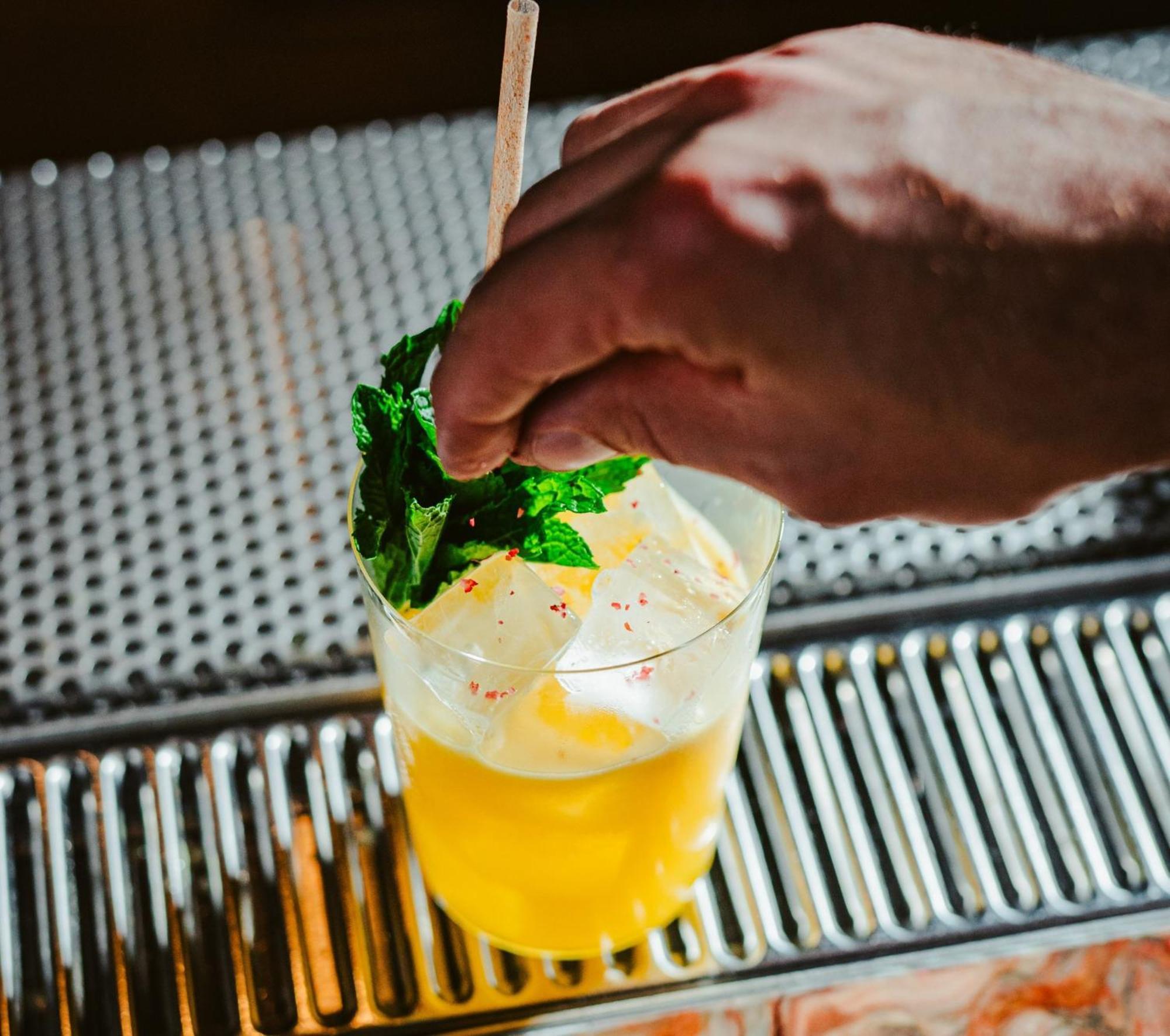 Vignette Collection Yours Truly Dc By Ihg واشنطن المظهر الخارجي الصورة A bartender garnishes a cocktail with mint.